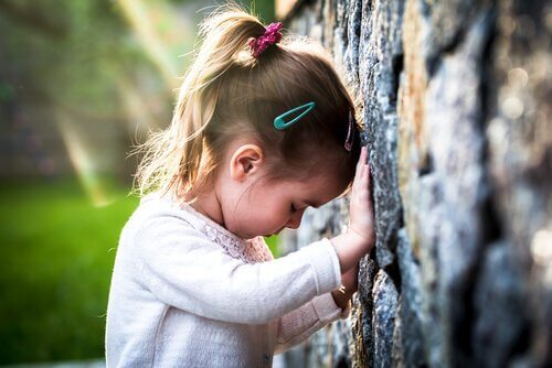 Ein trauriges Mädchen lehnt an einer Wand. 