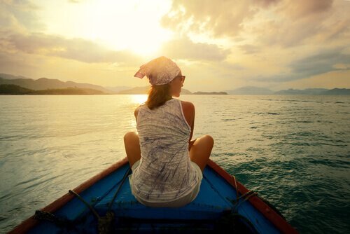 Ein Frau sitzt auf dem Bug eines Holzbootes.