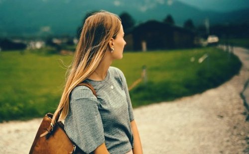 Frau auf einem Feldweg schaut über ihre Schulter zurück