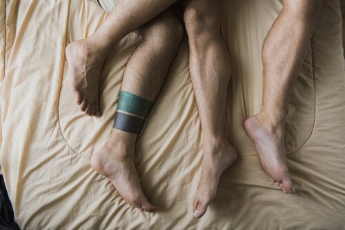 Vier Männerfüße im Bett