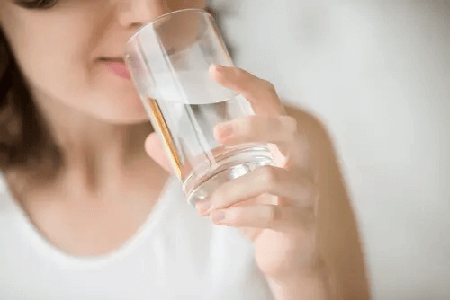 Frau trinkt ein Glas Wasser und befriedigt damit einen primären Impuls