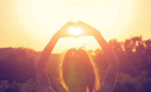 Hände formen ein Herz gegen die Sonne