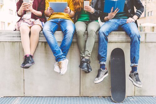 Eine Gruppe von Freunden mit Smartphone, Tablet und Buch