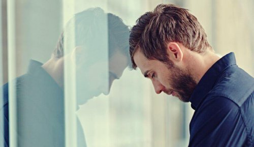 Mann stützt sich mit dem Kopf an einem Fensterglas