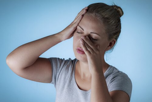 Frau mit Sinus-Kopfschmerzen fasst sich an Nase und Schläfe