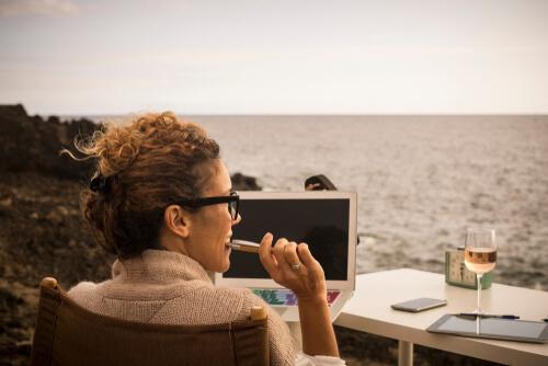 Nomadin mit Rechner und Wein am Meer