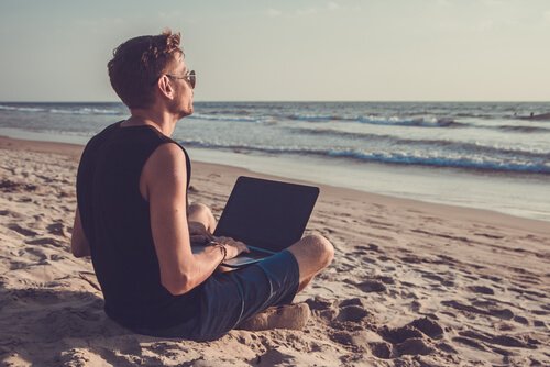 Mann mit Laptop am Strand
