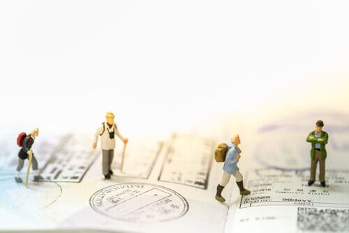 Kleine menschliche Figuren, die über einen Pass mit Rucksäcken und Spazierstöcken gehen.