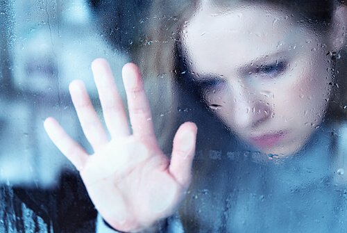 Die Angst, alleine zu sein, kennen viele: Traurige Frau legt ihre Hand an eine Scheibe
