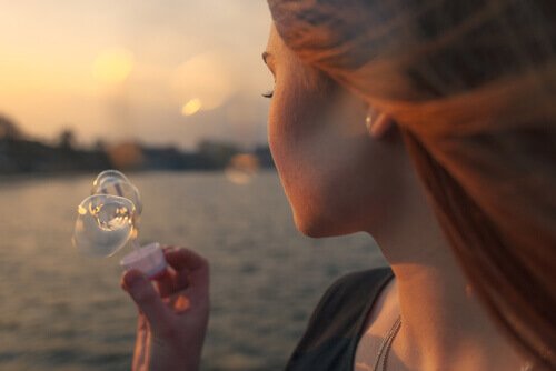 Frau macht Seifenblasen am See