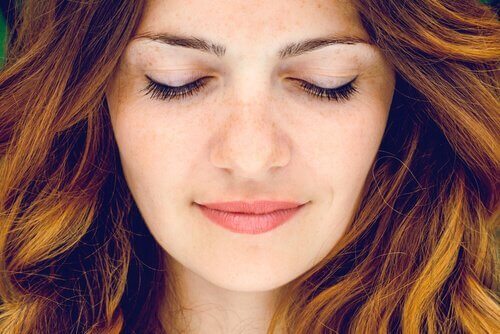 Eine Frau lächelnd mit geschlossenen Augen.