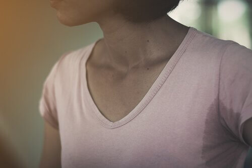 Ein Bild, das eine Frau in einem Hemd mit großen Schweißachselhöhlenflecken zeigt.