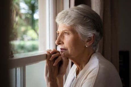 Eine ältere Frau schaut aus einem Fenster und braucht nicht-pharmakologische Therapie