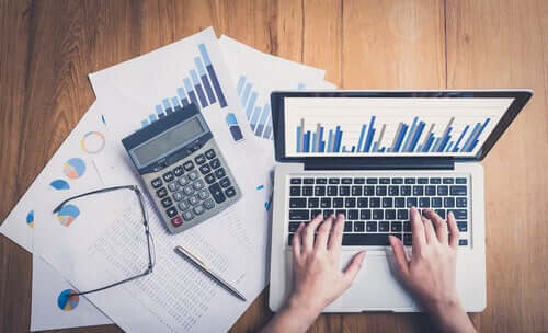 Hände auf Laptop neben Taschenrechner und Statistiken. Niemand ist unersetzbar!