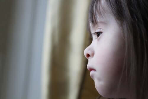 Ein Mädchen mit Down-Syndrom schaut aus dem Fenster.