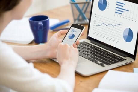 Eine Person, die ihr Telefon und Computer betrachtet. Statistische Begriffe auswerten.