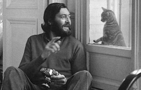 Cortázar sitzt am Fenster und spielt mit einer Katze auf der anderen Seite.