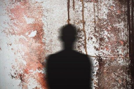 Der Umriss einer Person, die als Schatten auf eine Wand mit getrocknetem Blut geworfen wird.