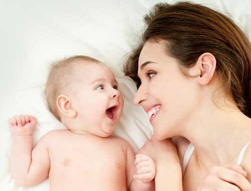 Eine Frau und ein Baby lächeln sich an, ein gutes Beispiel für Zuneigung und Bindung.