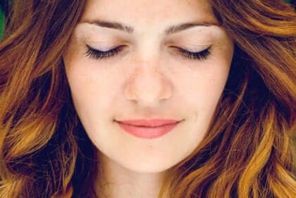 Eine Frau lächelnd mit geschlossenen Augen.