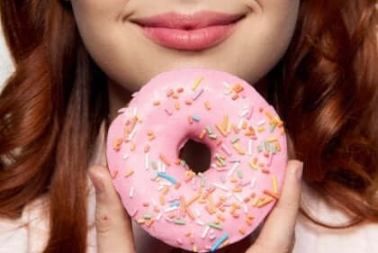 Eine Frau mit einem eiskalten rosafarbenen Donut.