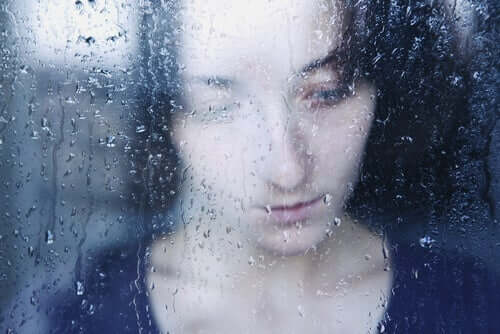 Eine traurig aussehende Frau hinter einem Fenster. Dein Gehirn reagiert auf Enttäuschung.