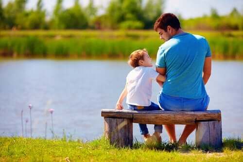 zu entschuldigen - Vater sitzt mit Sohn auf Bank am Fluss