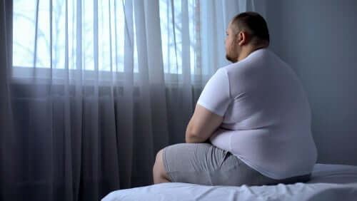Fettleibigkeit - übergewichtiger Mann sitzt auf einem Bett