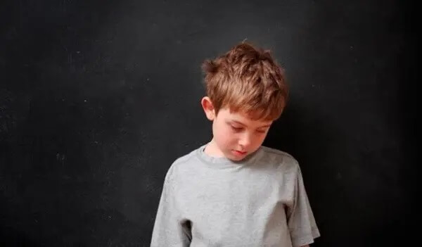 En trauriger Junge senkt den Kopf. SDQ-Fragebogen