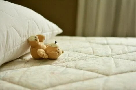 Ein Teddybärchen kippt von einem Kopfkissen.