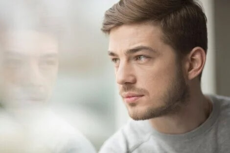 Ein junger Mann blickt aus dem Fenster und denkt über Einzigartigkeit nach.