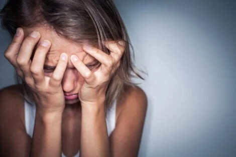 Eine Frau verspürt große Angst und birgt ihr Gesicht in beiden Händen.
