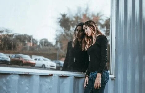 Enttäuschte Frau lehnt sich an eine Fensterscheibe. Warum enttäuschen mich Menschen?