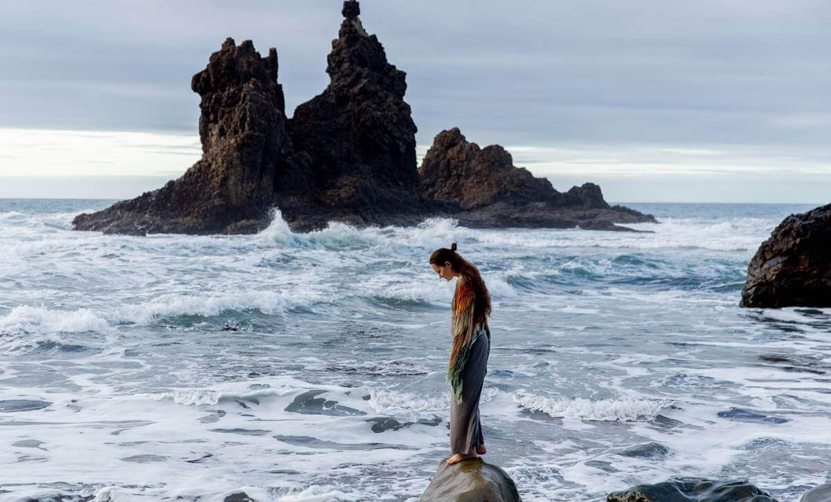 Alles schief - Frau auf einem Felsen im Meer