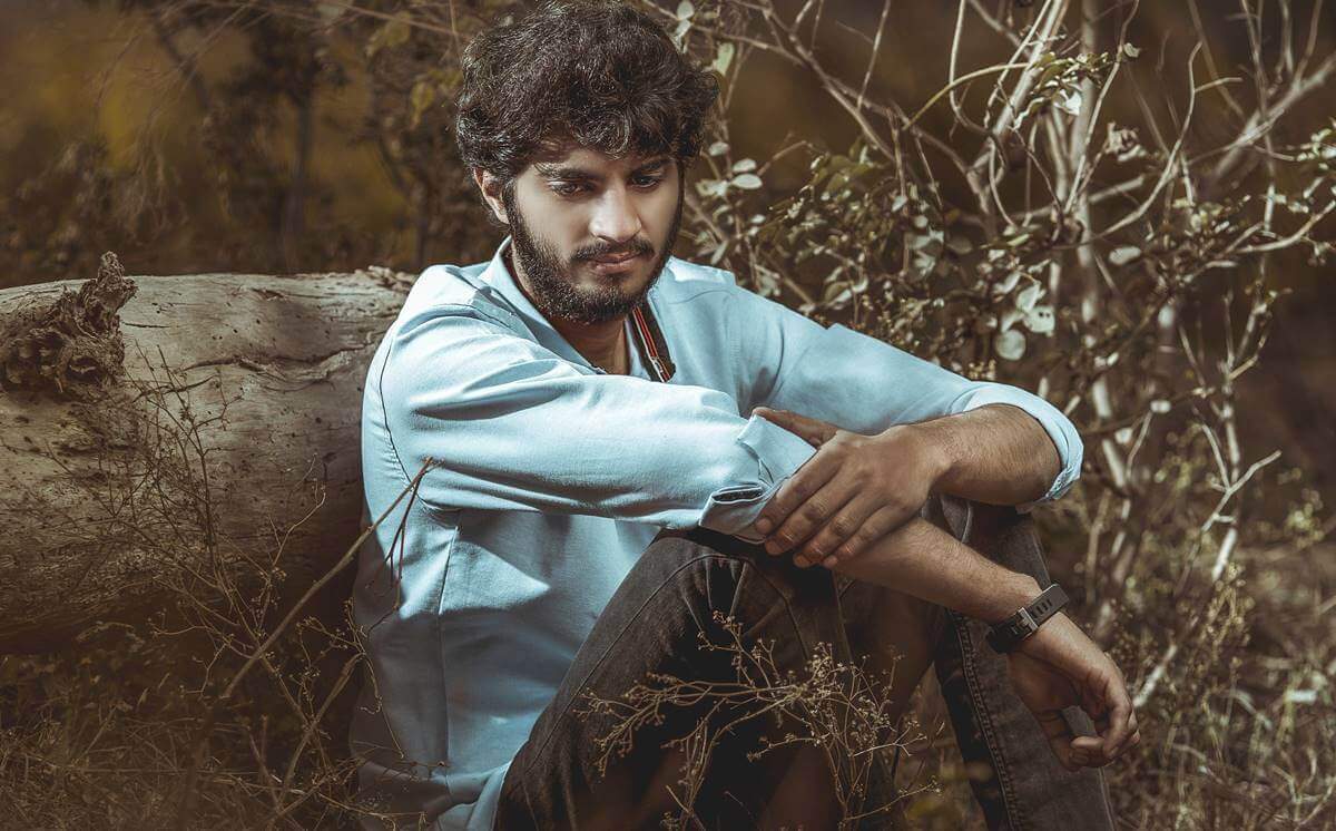 ohne Freunde - Mann sitzt alleine an einem Baumstamm