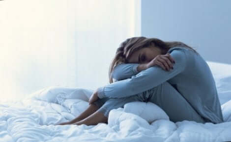 Prämenstruelle dysphorische Störung - Frau sitzt auf einem Bett