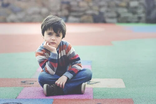 Ein Junge sitzt auf dem Spielplatz und denkt nach.