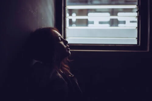 Eine Frau, die Angst hat, sitzt vor einem Fenster.
