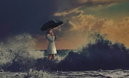 Eine Frau mit Regenschirm geht über den Ozean.