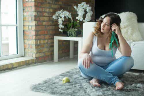 Die Verhaltensaktivierung beim Abnehmen - Frau sitzt auf dem Boden, neben sich einen Apfel